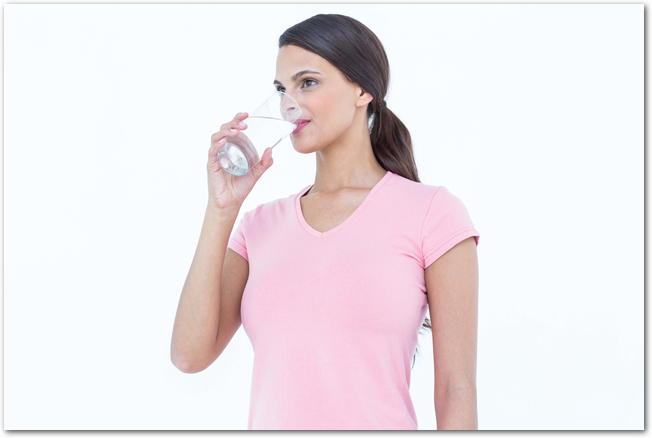 Pretty woman drinking glass of water on white background